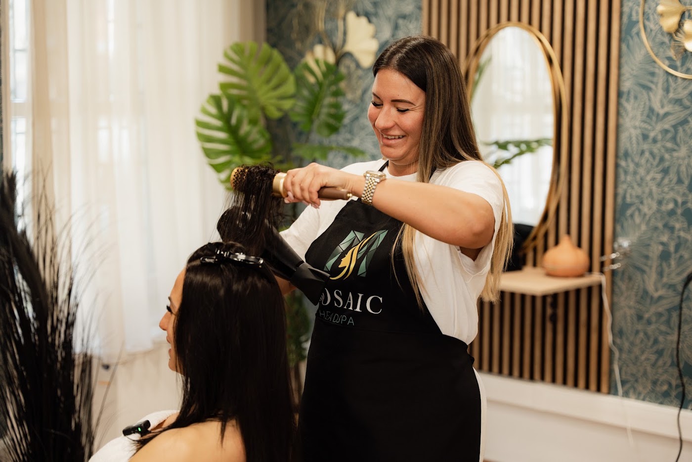 Mosolygó stylist professzionálisan szárítja a vendég haját